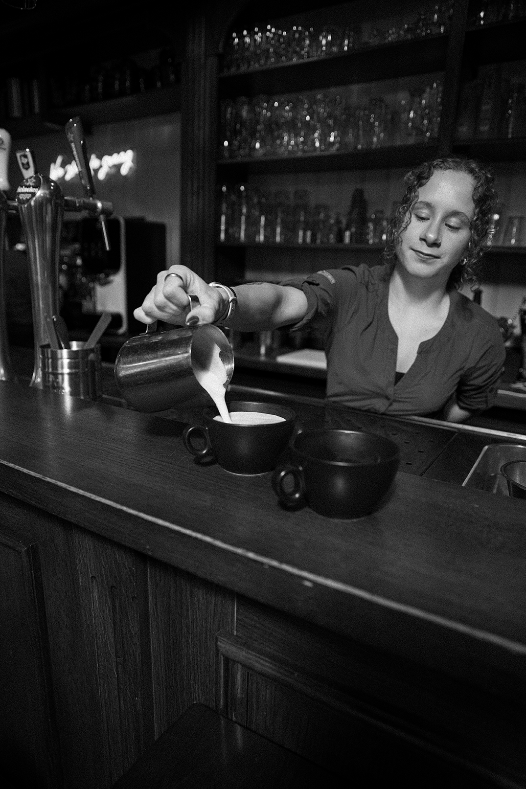 Medewerker schenkt melk in een kop koffie aan de bar